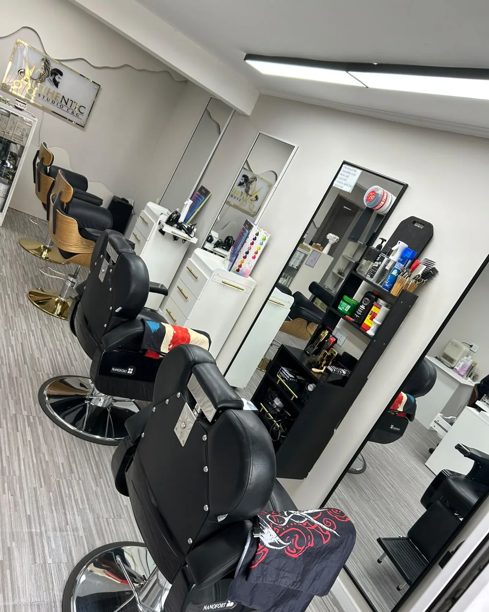 Interior de Authentic Studio C&G: sillones de barbería, espejos y el letrero dorado del estudio en Av. Zapadores 1229, Conchalí